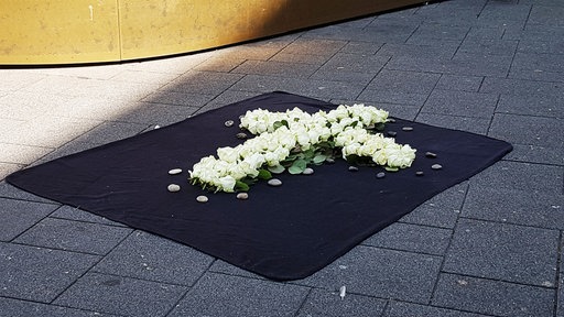 Ein weisses Blumenkreuz auf einem schwarzen Teppich