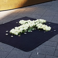 Ein weisses Blumenkreuz auf einem schwarzen Teppich