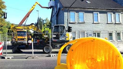 Haus mit Baufahrzeugen und Absperrung