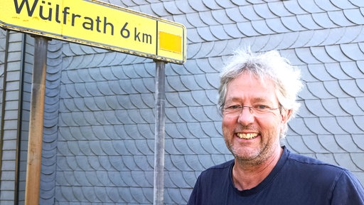 Mann steht vor Hauswand