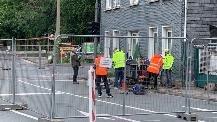 Männer in Sicherheitswesten beugen sich über die Straße