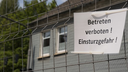Zu sehen ist ein Schild "Betreten verboten! Einsturzgefahr!", das am Zaun hängt.