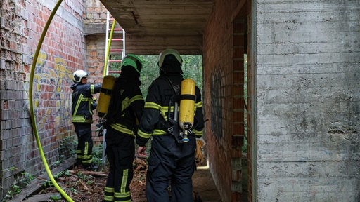 Drei Feuerwehrleute in der Ruine