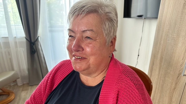 Eine ältere Frau mit kurzen grauen Haaren, die lächelt.