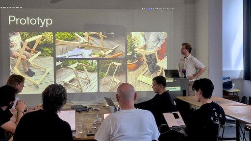 Auf einer Präsentation vor dem Uni-Kurs ist ein Prototyp aus Holz zu sehen