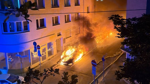 Autos brennen in der Nacht zwischen Häusern