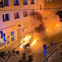 Autos brennen in der Nacht zwischen Häusern