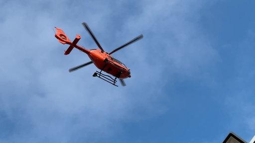 Ein Rettungshubschrauber fliegt vor blauem Himmel.
