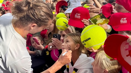 Alexander Zverev unterschreibt im Gesicht eines Mädchens