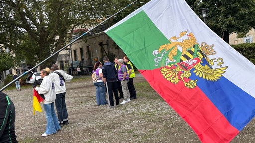 Eine Fahne an einem Stock zeigt eine Kombination aus der Flagge des Königreichs Sachsens und der Flagge von Russland.