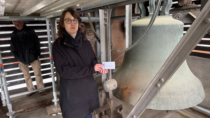 Theodora Beer steht neben beschädigter Glocke 