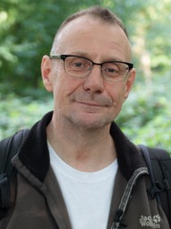 Ein Mann mit Brille im Porträt.