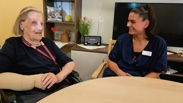 Die zu pflegende Gisela Nentwig aus Bielefeld und neben ihr sitzt die stellvertretende Pflegedienstleiterin Aysel Acer.