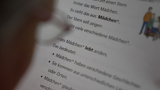 Eine Prüferin liest einen Text in Leichter Sprache.