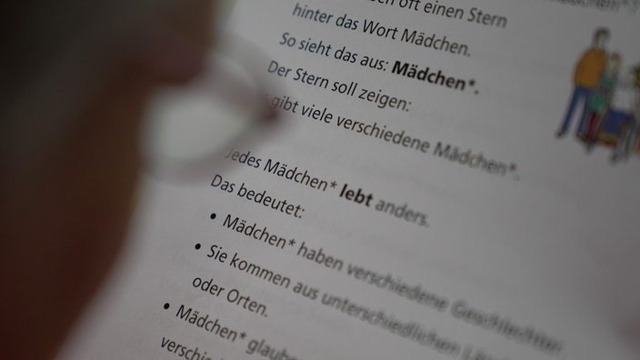 Eine Prüferin liest einen Text in Leichter Sprache.