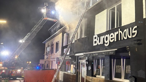 Starker Rauch kommt aus einem Haus in Löhne. Feuerwehrleute stehen auf einer Drehleiter und löschen den Brand.