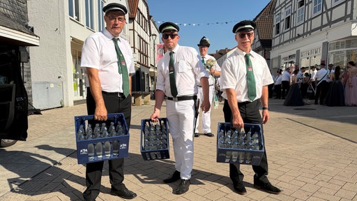 Drei Schützen halten Wasserkisten in ihren Händen
