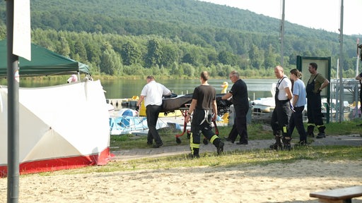 Rettungskräfte schieben eine Trage ans Ufer des Schiedersees