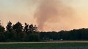 Eine Rauchwolke steigt hinter Bäumen empor