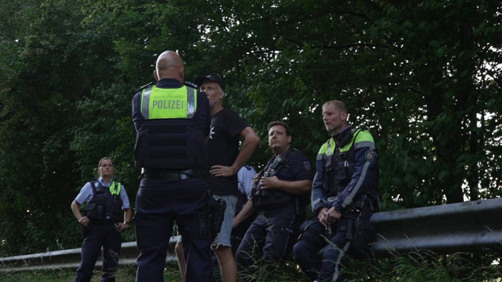 Polizeibeamte sitzen auf einer Leitplanke