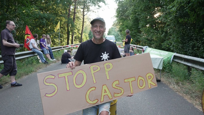 Ein Mann hält ein Schild fest mit der Aufschrift "Stopp Castor"