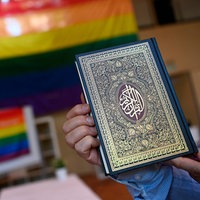 Ein Koran vor einer Prideflagge