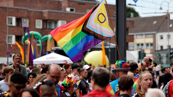 Teilnehmer des Umzugs mit einer Progressive-Pride-Flag zu sehen bei der CSD-Parade im Rahmen des Cologne Pride 2024. 