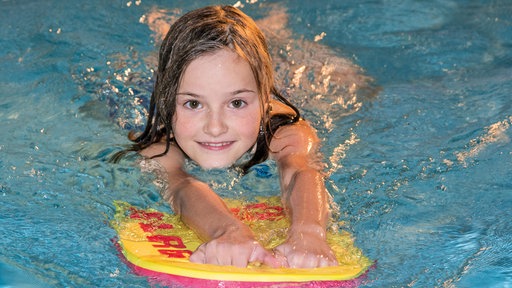 Kind schwimmt mit Schwimmmatte
