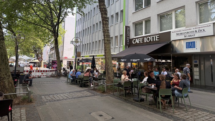 Die Kleppingstraße ist voller Menschen die im Außenbereich der Cafes sitzen.