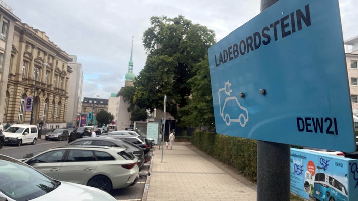 Mehrere Autos parken am Straßenrand, daneben ein Schild mit der Aufschrift Ladebordstein DEW21