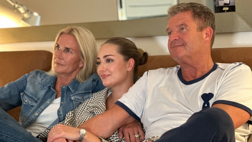 Maxine Reuker mit ihren Eltern auf der Couch.