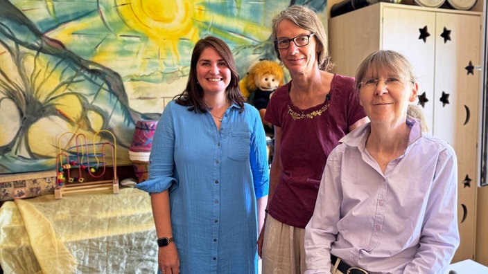 Jenny Vierhaus, Petra Kern und Kerstin Hübner stehen und sitzen nebeneinander und schauen in die Kamera.