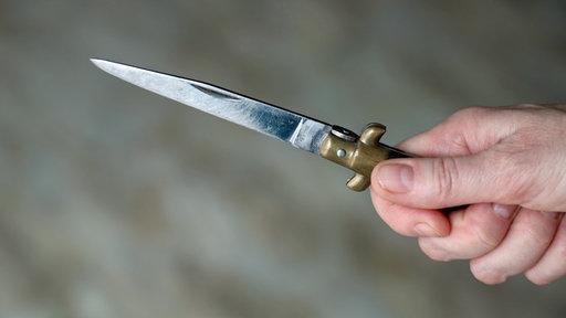 Eine Hand hält ein spitzes Messer.
