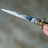 Eine Hand hält ein spitzes Messer.