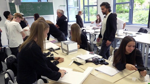 Schüler und Schülerinnen in einem Klassenzimmer schneiden und hantieren an Styroporplatten