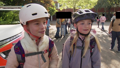 Zwei Mädchen stehen nebeneinander auf einem Schulhof