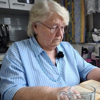 Ältere Frau sitzt in ihrer Wohnung und liest.