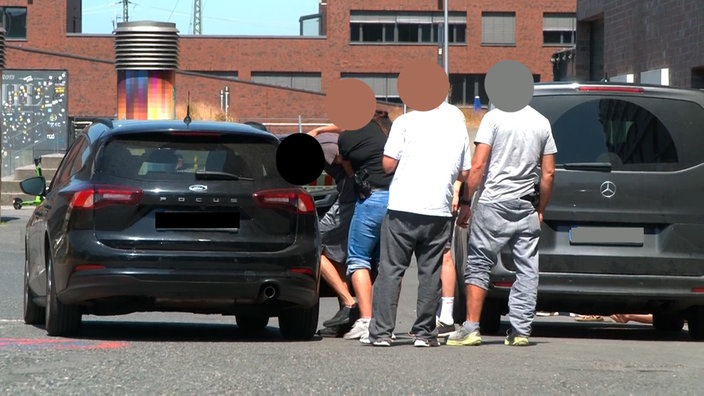 Ein Mann wird von einer Beamtin in Zivil in ein Auto befördert.