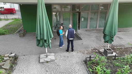 Das Ladenlokal des Grünen Salons von außen, zwei Personen stehen davor.