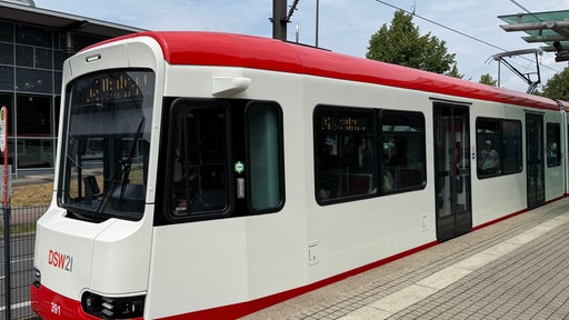 Die rot-weiße Stadtbahn steht an einer Haltestelle in Dortmund