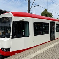 Die rot-weiße Stadtbahn steht an einer Haltestelle in Dortmund