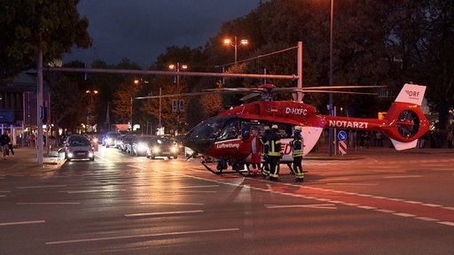 Ein roter Rettungshubschrauber steht mitten auf dem Dortmunder Südwall. Dahinter stehen Autos.