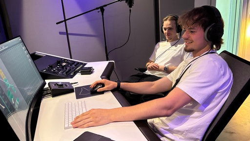 Die Producer Jonny und Steffen hören mit Kopfhörern ein Lied ab.