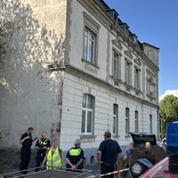 Polizei und Anwohner halten sich vor dem geräumten Mehrfamilienhaus auf