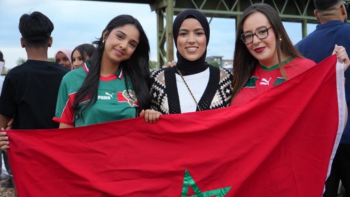 Drei Frauen stehen mit Marokko-Flagge vor der Leinwand im Hafengarten