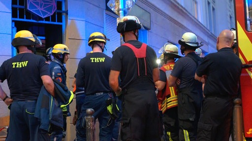 Einsatzkräfte des THW und der Feuerwehr Dortmund stehen vor einem Gebäude.