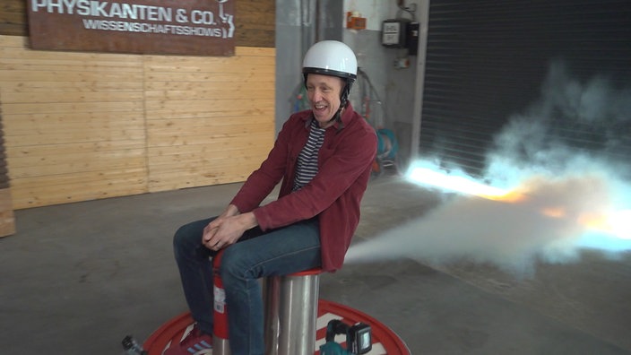 Marcus Weber sitzend auf einer Erfindung, die sich mithilfe von Physik fortbewegt