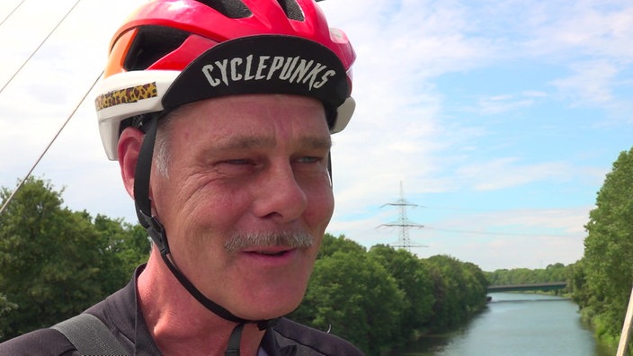 Michael Höffken trägt einen Fahrradhelm und schmunzelt.