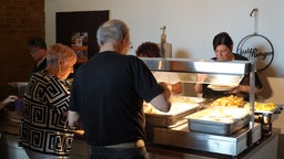 Gäste stehen an einem Spargelbuffet und haben Teller in der Hand