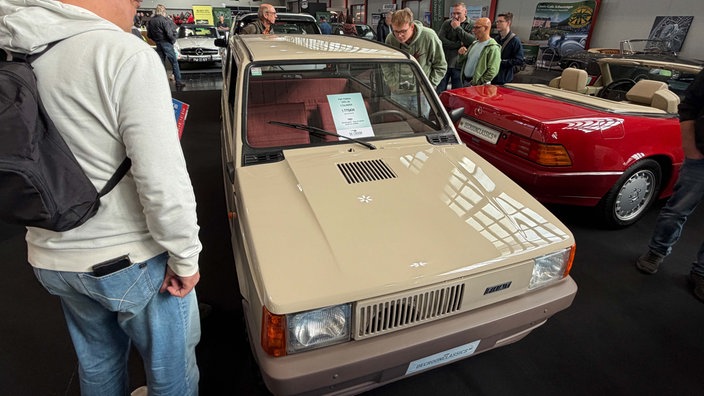 Ein beiger, älterer Fiat Panda auf einer Messe.